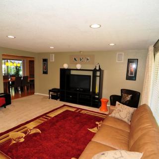 A cozy living room with a large couch and television, featuring modern decor and a vibrant red carpet.