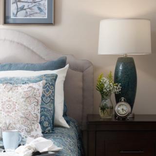 A cozy bedroom scene with a stylishly arranged bed and nightstand featuring a lamp and decorative items.