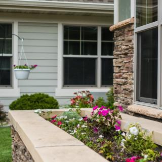A beautifully landscaped garden with colorful flowers in front of a house with a stone facade.