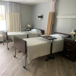 A tranquil hospital patient room featuring two beds and a soothing color scheme.