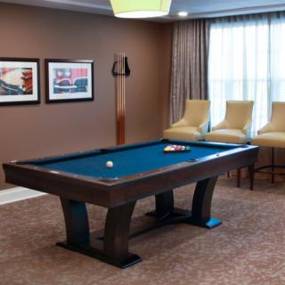 A well-furnished game room featuring a pool table, chairs, and artwork on the walls.