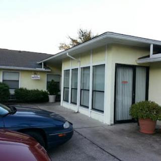 A small building with adjacent parking spaces and cars.