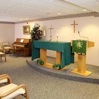 A small chapel interior with an altar, pulpit, and organ.