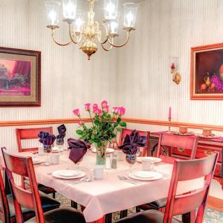 A cozy dining room with a beautifully set table and floral centerpiece under a warm chandelier light.