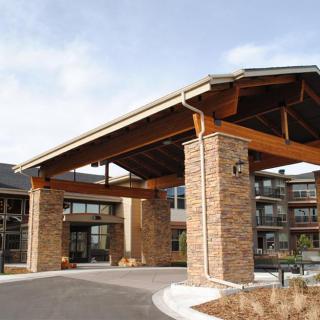 The entrance of a modern hotel building with stone pillars and a covered driveway.