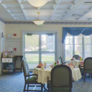 A dining room with tables and chairs, decorated with bright curtains and a view of the outdoors.