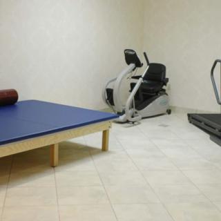 A small gym room with a treadmill, exercise bike, and a mat for workouts.