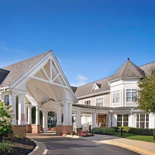 A large residential building with a covered entrance and clear blue sky.