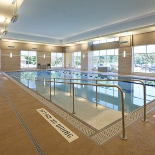 A modern indoor swimming pool area with ample lighting and comfortable surroundings.
