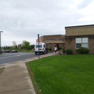 A cloudy day outside a building with a van parked and people walking.