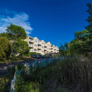 A scenic view of an apartment building surrounded by lush greenery under a clear blue sky.