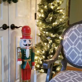 A festive indoor holiday scene featuring a nutcracker and a Christmas tree adorned with lights.