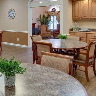 A cozy dining area with round tables, wooden chairs, and small potted plants.