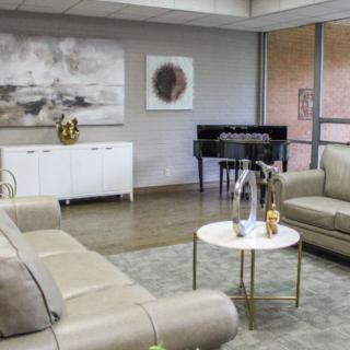 A modern living room featuring a piano, stylish sofas, and contemporary artwork.