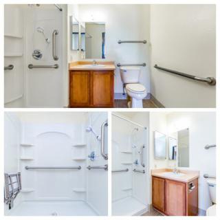 An accessible bathroom equipped with grab bars, a spacious shower, and a sink area.