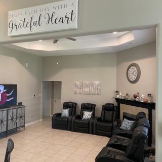A cozy living room with leather seating, a TV, and decorative wall art.