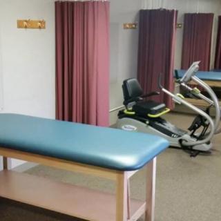 A physical therapy room with a treatment table and exercise equipment.
