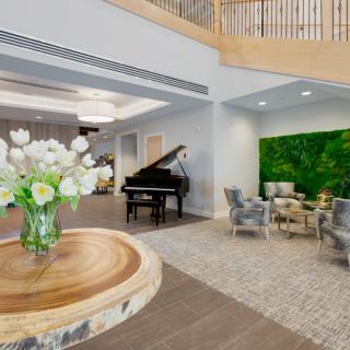 A modern lobby with a grand piano, elegant seating, and fresh flowers on a table.