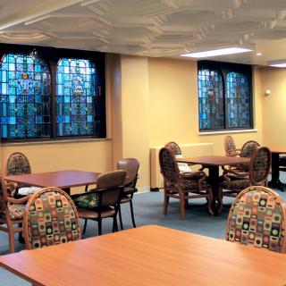 An interior view of a library with tables, chairs, and stained glass windows.