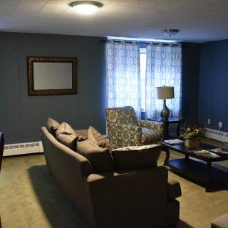 A cozy living room with a sofa, armchair, coffee table, and decorative elements like wall art and curtains.