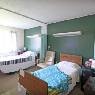 An empty hospital room with two patient beds and medical equipment.