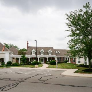 A suburban residential building with a cloudy sky and trees in the background.