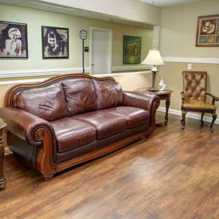 A cozy living room with a leather couch, wooden flooring, and decorative artwork.