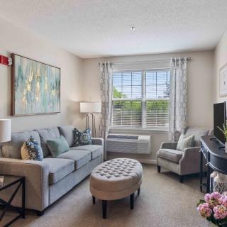 A cozy living room with a sofa, armchair, and a large window.
