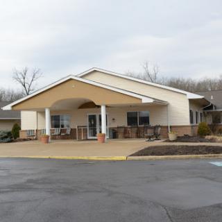 A welcoming residential building with a shaded entryway and landscaped surroundings.
