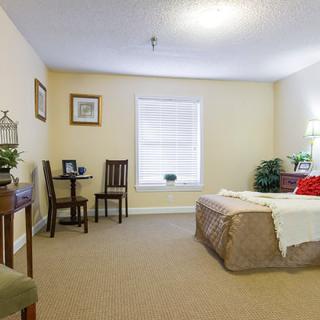 A cozy and well-lit bedroom with a bed, desk, and chairs.