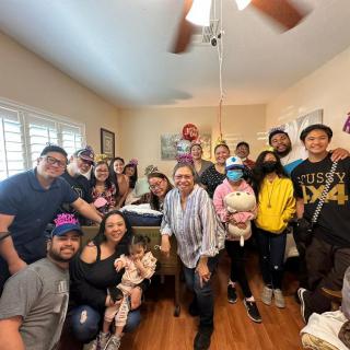 A joyful family gathering with everyone smiling for a group photo indoors.