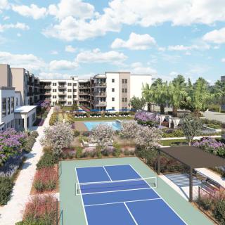 A modern apartment complex featuring a tennis court and well-maintained landscaping.