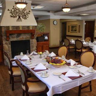 A beautifully arranged dining room showcasing an inviting table setting and a warm fireplace.