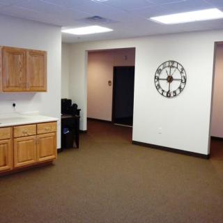 Empty office space with wall clock and wooden cabinets.