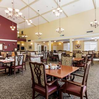 A spacious dining area with neatly arranged tables and chairs, featuring elegant lighting and a warm ambiance.