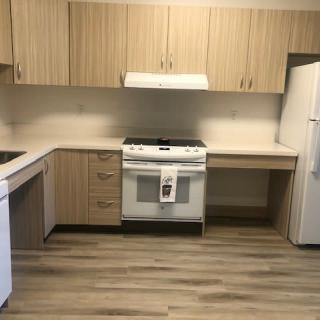 A modern kitchen with wood cabinets, featuring a stove, refrigerator, and dishwasher.