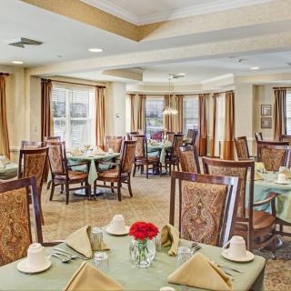 An elegant dining room with neatly arranged tables and chairs, adorned with decorative elements and natural light.