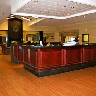 A spacious hotel lobby featuring a central reception desk with wooden accents.