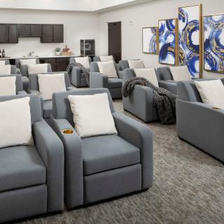 A modern lounge area with plush reclining chairs, adorned with abstract artwork on the walls.