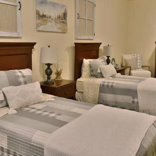 A cozy bedroom with twin beds, elegant lamps, and a comfortable armchair.