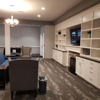 A cozy living room area featuring comfortable seating, a television, and stylish bookshelves.