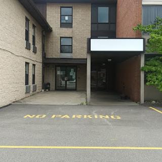 A view of a building entrance with a clear 'No Parking' sign painted on the ground.