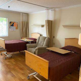 A view of a hospital patient room featuring two adjustable beds and a recliner.