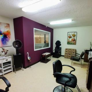 A well-lit salon interior with chairs, a large mirror, and hair styling tools.