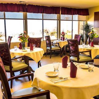 A well-lit restaurant dining room with elegantly set tables and large windows offering a scenic view.