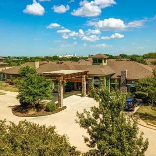 Aerial view of a residential building surrounded by trees under a clear blue sky.