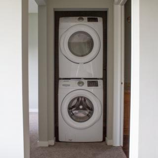A stacked washer and dryer unit in a home hallway.
