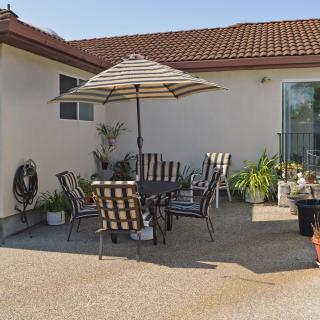 A cozy backyard patio with striped chairs and an umbrella for shade.