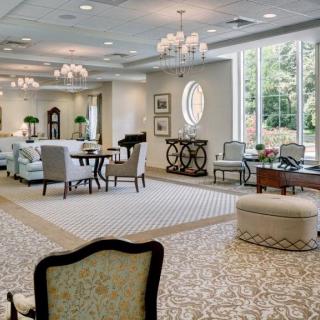 A spacious and elegantly designed lounge with various seating areas, chandeliers, and large windows.