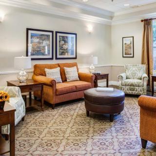 A cozy living room with a brown sofa, armchairs, and a central coffee table surrounded by decorative artwork.